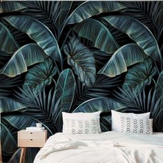 a bed sitting under a large green leafy wall mural