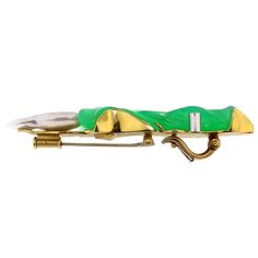 a green and gold brooch with two toothbrushes on it's side