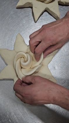 two hands are making star shaped dough