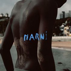 a man standing on the beach with his back turned to the camera and words written in blue ink