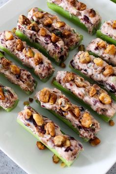 several celery sticks with nuts and cheese on them sitting on a white plate