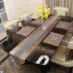 a dining room table with chairs and a vase filled with yellow flowers on top of it