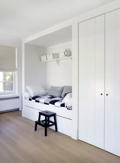 a room with white walls and wooden flooring has a bench in front of the window