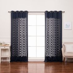 a living room filled with furniture and a window covered in black sheer curtains next to a white chair