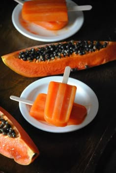 two slices of papaya and one piece of melon on a plate with toothpicks