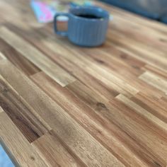 a wooden table with a blue cup on it's end and a book in the background