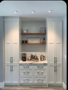 a kitchen with gray cabinets and white counter tops, coffee maker on the far wall