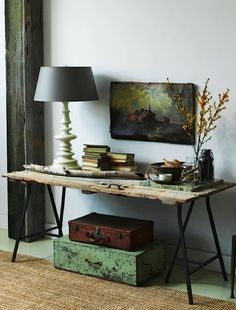 a room with a table, chair and painting on the wall next to a lamp