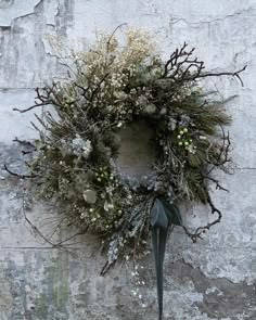 a wreath is hanging on the side of a stone wall with snow and greenery