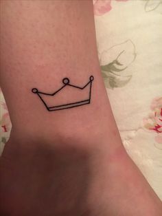 a small crown tattoo on the ankle