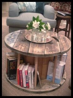 a coffee table made out of pallet wood with flowers on top and books in the middle