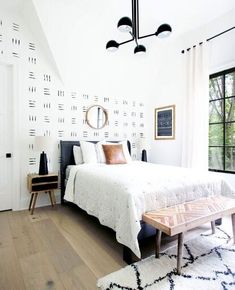 a bedroom with white walls and wood flooring has a large bed in the center