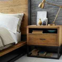 a bedroom with a bed, nightstand and lamp on top of the night stand in front of the bed