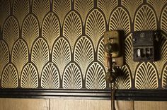 an old phone is on the wall next to a wooden paneled wall with art deco design