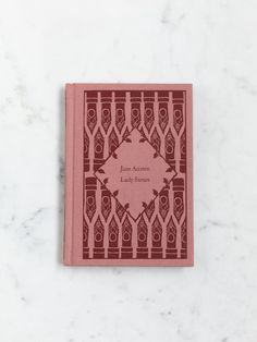 a pink book sitting on top of a white counter next to a marble wall and floor