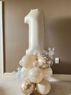 a balloon tower with white and silver balloons in the shape of a number one on it