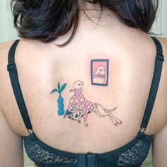 a woman with a tattoo on her back that has an image of a dog and a vase