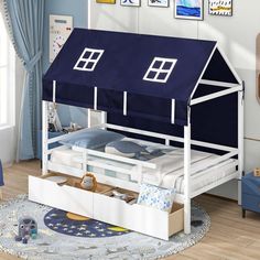 a child's bed with a blue roof on top and a white frame underneath it