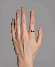 a person's hand with a black ring on their left thumb and the middle finger