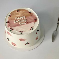 a birthday cake with pink frosting and strawberrys on it next to a knife