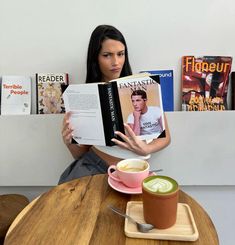 a woman sitting at a table with a book and cup of coffee in front of her