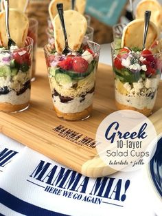 small cups filled with food sitting on top of a wooden tray next to crackers