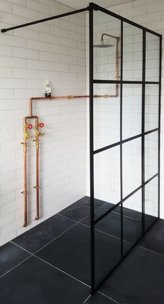 a bathroom with black tile flooring and exposed pipes on the wall next to it