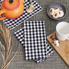 tea and cookies on a table with black and white gingham cloth, orange teapot