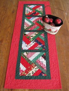 a table runner with apples on it next to a bowl of red and green ornaments