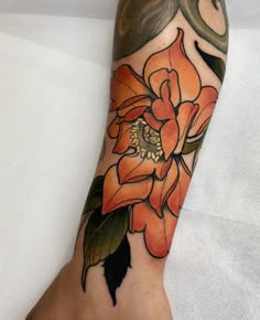 an orange flower with green leaves on the arm