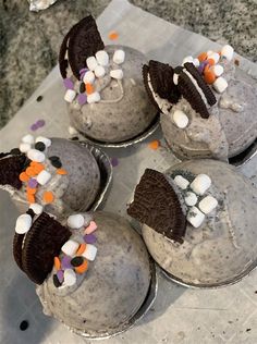 four cupcakes decorated with oreo cookies and marshmallows