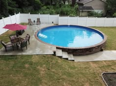 an above ground swimming pool with patio furniture and umbrellas in the middle of it