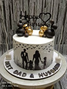 a birthday cake decorated with family silhouettes and gold accents on top of a table