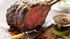 a large piece of meat sitting on top of a cutting board next to some spices