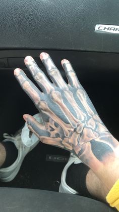 a man with his hand in the center console of a car, holding up an arm tattoo