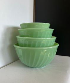 three green bowls sitting on top of a counter