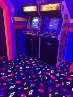 two arcade machines sitting next to each other on top of a floor covered in neon colored tiles