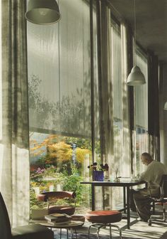 a man sitting at a table in front of large windows