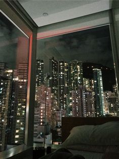 a bedroom with a view of the city at night from it's window sill