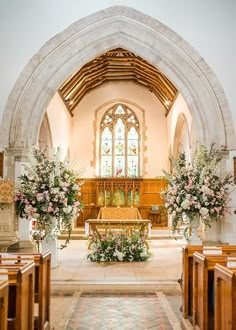 the inside of a church with flowers in vases on the alter and pews