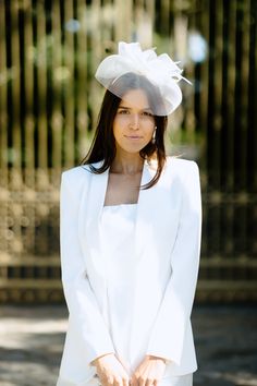 a woman in a white suit and hat posing for the camera with her hands on her hips