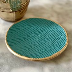 a blue and gold plate sitting on top of a table next to a metal container