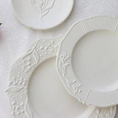 three white plates sitting next to each other on top of a cloth covered tablecloth