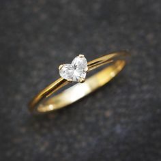 an engagement ring with two heart shaped diamonds on the top, sitting on a gray surface