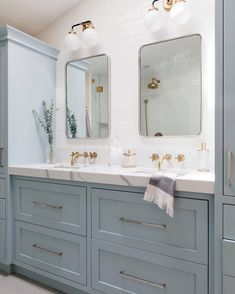 two sinks and mirrors in a bathroom with blue cabinets