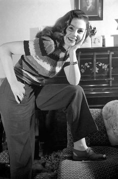 a woman sitting on top of a couch next to a chair