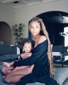 a woman sitting on top of a couch holding a baby