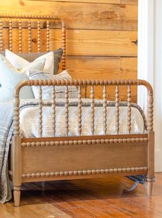 a bed with wooden headboard and foot board on the floor in front of a wood paneled wall