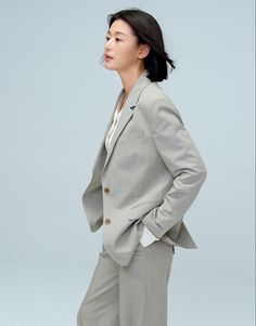 a woman in a gray suit and white shirt is standing with her hands on her hips