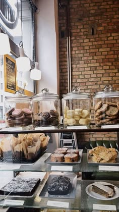 a display case filled with lots of different types of pastries and desserts next to a brick wall